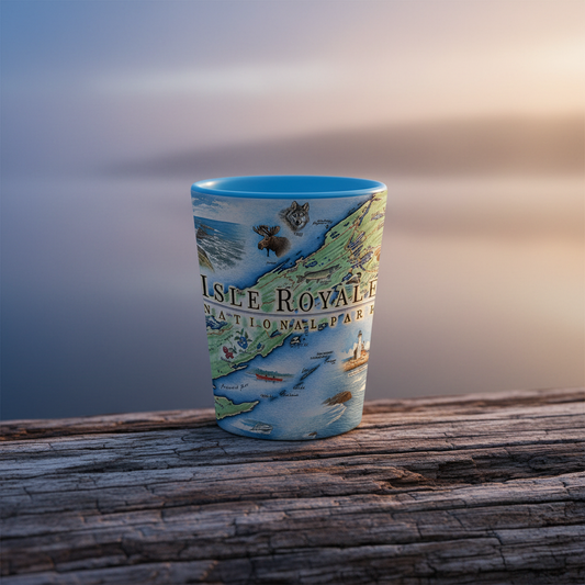 A ceramic shot glass featuring a detailed illustration of Isle Royale National Park, resting on a weathered wooden log with a soft-focus background of water and sky.