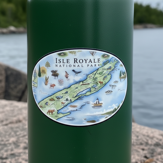 A close-up of a dark green cylindrical water bottle with an oval sticker reading 'ISLE ROYALE NATIONAL PARK' and a colorful illustrated map of the island, set against a blurred outdoor water and shoreline background.