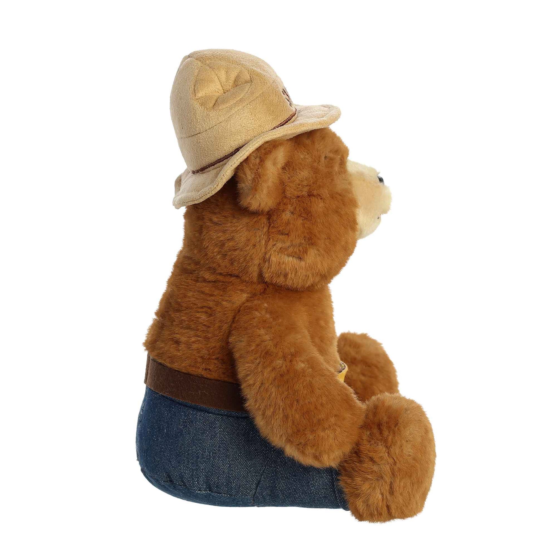 Plush teddy bear wearing a hat and blue pants on a white background