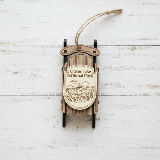 Crater Lake national Park sled ornament laid against rustic, white shiplap boards