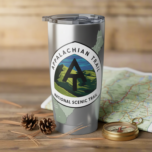 Stainless steel Tumblr with Appalachian Trail map and logo set on a rustic table with a map, compass and natural elements.