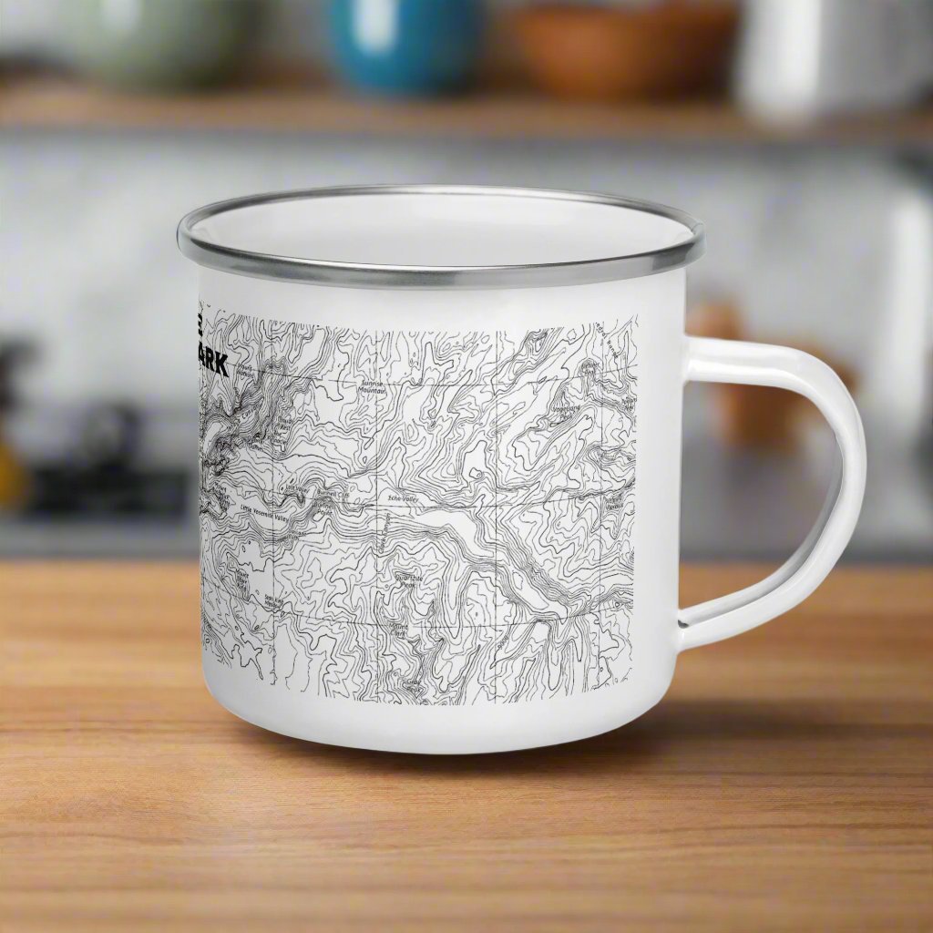 Side view of a white Yosemite national Park enamel camping mug on a wood counter