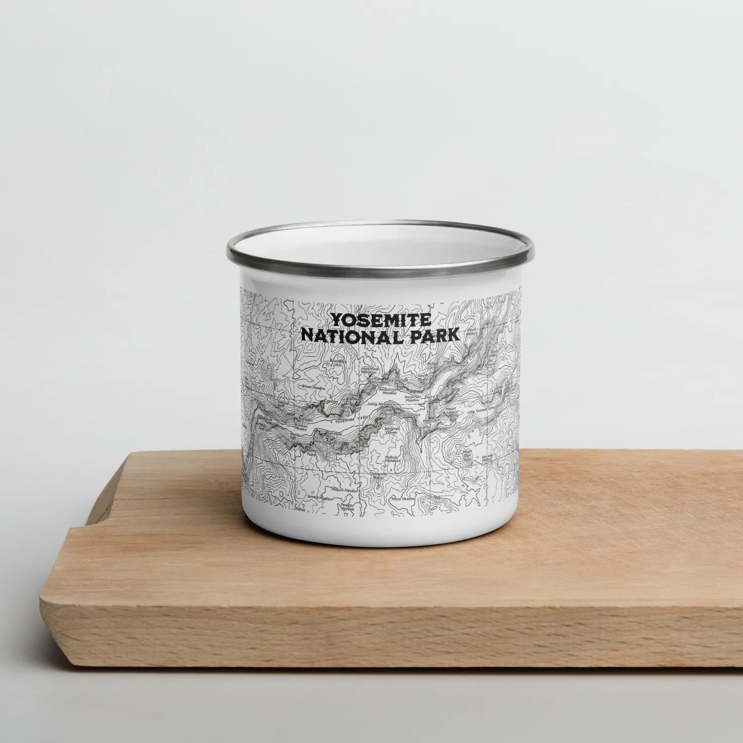 Yosemite national Park topographic enamel camping mug, sitting on a wood board against a white background
