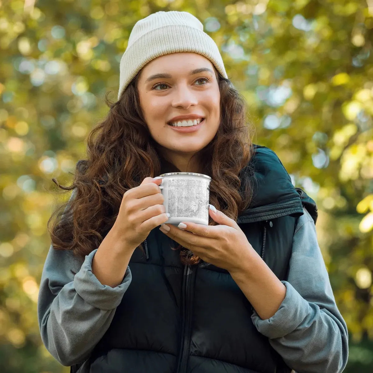 Female individual holding a Yosemite national Park topographical enamel mug while in the woods